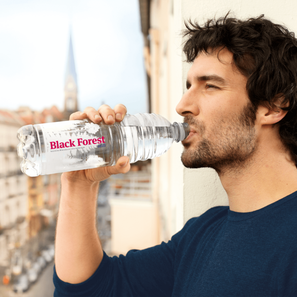 Junger Mann trinkt aus Black Forest Flasche